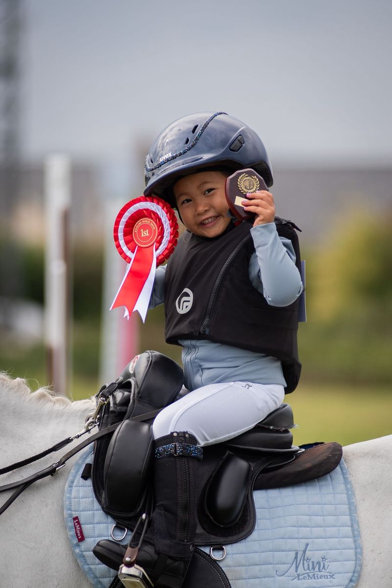 Young child riding a pony with an inky dinky sadle